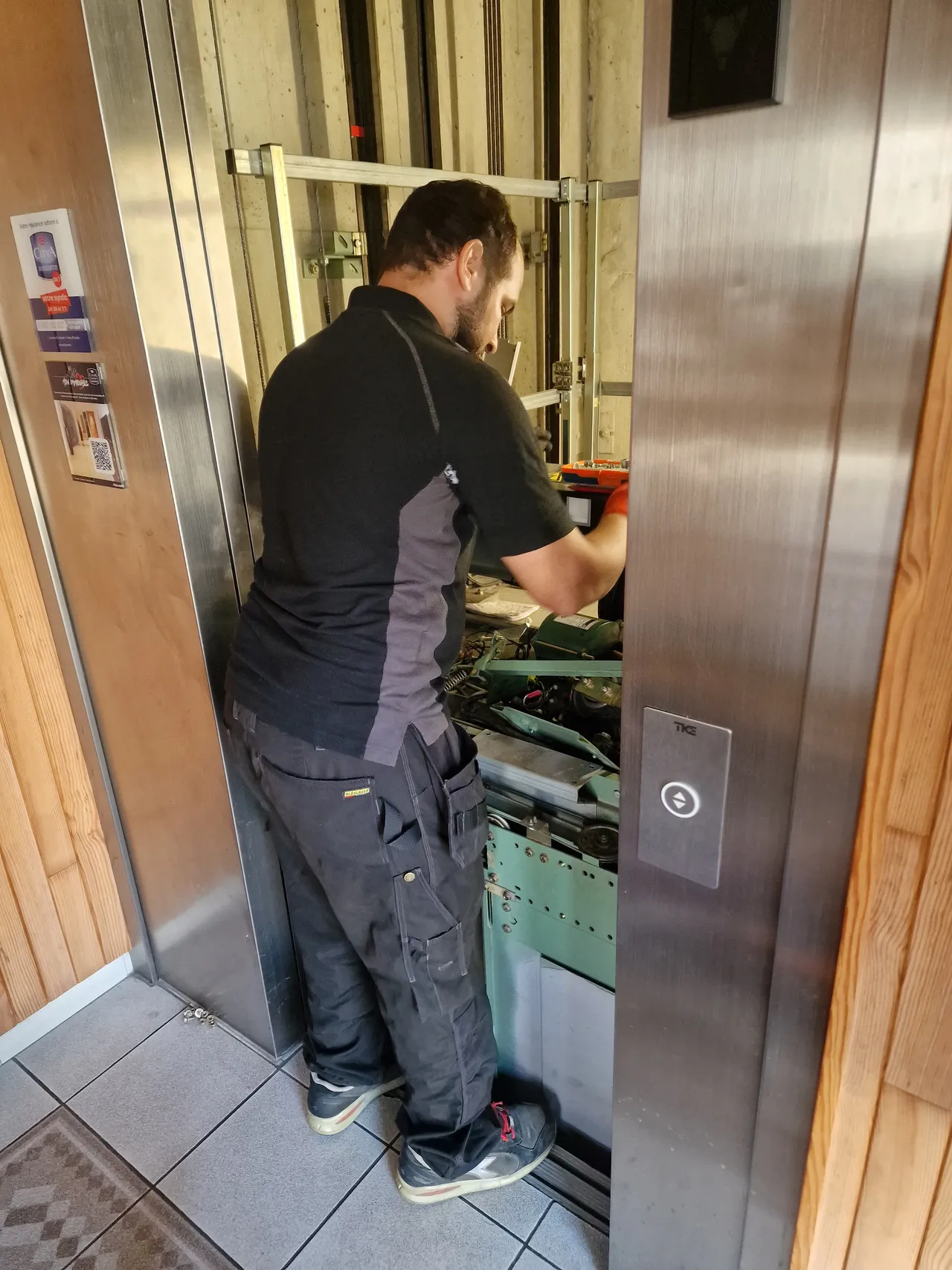 Technicien intervenant sur le mécanisme d’un ascenseur, depuis le palier